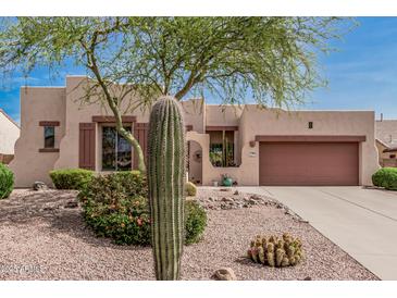 Charming desert landscaping complements this tan home with a two-car garage at 8307 S Desert Preserve Ct, Gold Canyon, AZ 85118