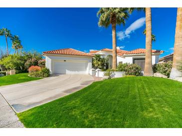 Charming single-story home featuring a well manicured lawn, beautiful palm trees, and an attached two-car garage at 11736 E Del Timbre Dr, Scottsdale, AZ 85259