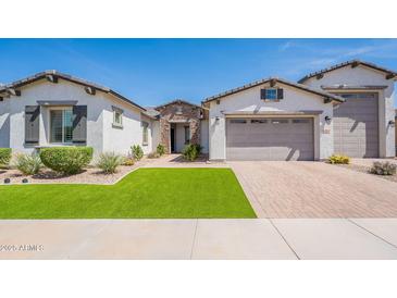 Charming single-story home boasts a well-manicured lawn and a neutral-toned exterior with a brick driveway at 21617 S 229Th Way, Queen Creek, AZ 85142