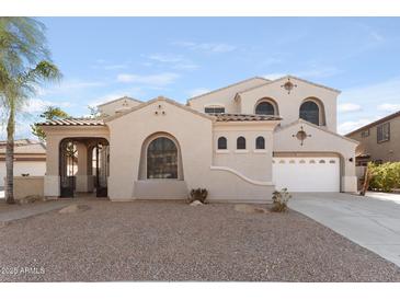 Inviting home exterior with neutral stucco, arched windows, tile roof, two-car garage and rock landscaping at 3557 S Halsted Ct, Chandler, AZ 85286