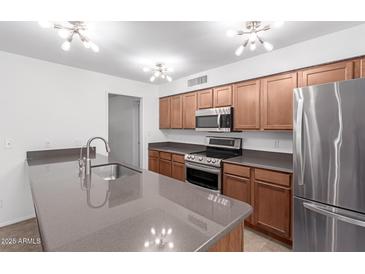 Open kitchen with stainless steel appliances, light countertops, and wood cabinetry at 4445 E Coconino St, Phoenix, AZ 85044