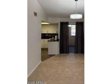 Inviting living room featuring neutral carpet, modern lighting, and seamless access to a well-appointed kitchen area at 461 W Holmes Ave # 374, Mesa, AZ 85210