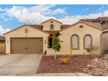 Charming single-story home featuring a tile roof, arched windows, and a low-maintenance desert landscape at 6904 W Ashby Dr, Peoria, AZ 85383