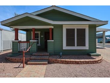 Charming green home with inviting front porch and well-maintained brick landscaping and walkway at 6960 W Peoria Ave # 237, Peoria, AZ 85345