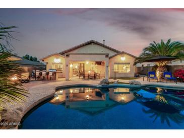 Gorgeous backyard pool with patio, lounge chairs, outdoor kitchen, and desert landscaping is perfect for entertaining at 12526 S 176Th Ave, Goodyear, AZ 85338