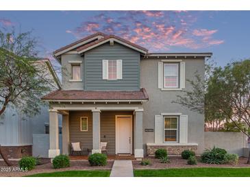 Charming two-story home featuring a covered porch, neutral stucco, and beautiful desert landscaping at 21073 W Sunrise Ln, Buckeye, AZ 85396