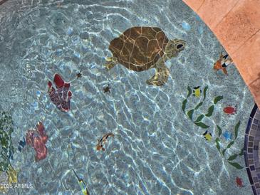 A sparkling pool with whimsical underwater turtle and fish mosaic tile art provides an eye-catching custom finish at 10846 E Quartet Ave, Mesa, AZ 85212