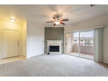 Light-filled living room featuring a fireplace, neutral carpet, and sliding glass doors to balcony at 16013 S Desert Foothills Pkwy # 2055, Phoenix, AZ 85048