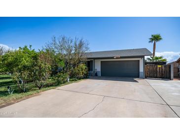 Charming single-story home featuring a gray two-car garage, mature trees, and a concrete driveway at 18829 N 23Rd Ave, Phoenix, AZ 85027