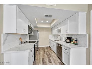 Modern kitchen with white cabinets, stainless steel appliances, and stylish countertops and flooring at 3154 E Clarendon Ave, Phoenix, AZ 85016