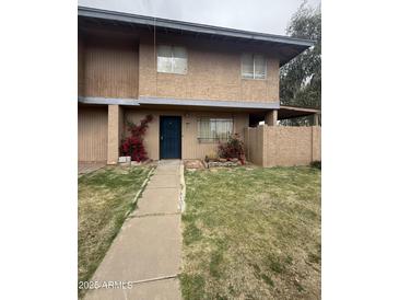 Inviting two-story home with a tidy front yard, beautiful flowering bushes and a blue door at 4219 N 69Th N Ln # 1319, Phoenix, AZ 85033