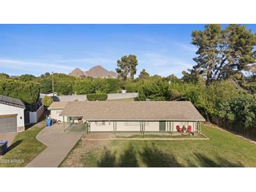 Charming single-story home with a covered front porch and lush green lawn set against a mountain backdrop at 4813 N 28Th Pl, Phoenix, AZ 85016