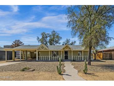 Charming home with a covered front porch, large trees and desert landscaping at 1719 E Pinchot Ave, Phoenix, AZ 85016