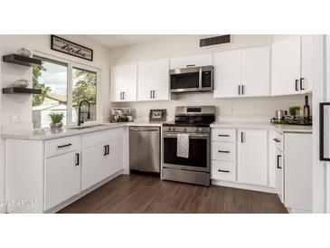 Bright kitchen with white cabinets, stainless appliances, and granite countertops provides a modern and clean cooking space at 1750 W Mohawk Ln, Phoenix, AZ 85027