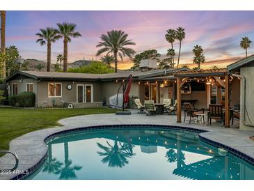 A beautiful outdoor pool area with palm trees and a covered patio, perfect for relaxation and entertainment at 13631 N Canterbury Dr, Phoenix, AZ 85023