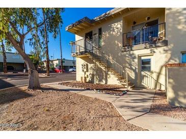 View of condo building featuring wrought iron stairs and walkway through desert landscaping on a bright sunny day at 14261 N Oakwood Ln, Fountain Hills, AZ 85268