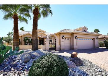 Inviting desert home featuring a gated entrance, mature palm trees, and a three car garage at 15061 W Pinchot Ave, Goodyear, AZ 85395