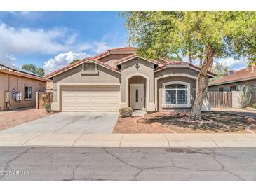 Charming single-story home featuring a low maintenance desert landscape, two car garage, and cozy covered porch at 15856 W Calavar Rd, Surprise, AZ 85379
