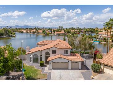 Waterfront home featuring a two-car garage, tile roof, and meticulously maintained landscaping at 3520 N 110Th Ave, Avondale, AZ 85392