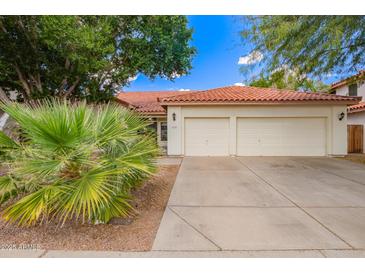 Charming single-story home with a two-car garage, beautiful desert landscaping, and a classic red tile roof at 5428 W Wethersfield Dr, Glendale, AZ 85304