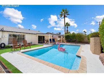 Backyard pool with flamingo float, outdoor seating, and tropical landscaping creates a relaxing oasis at 7502 E Princeton Ave, Scottsdale, AZ 85257