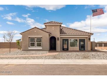 Charming single-story home featuring a desert landscape, tile roof, and an American flag on the front yard at 18848 N Barano Dr, Maricopa, AZ 85138