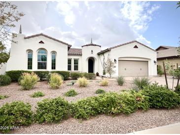 Charming white single-story home with a well-manicured desert landscape, arched windows, and a two-car garage at 20525 W Hamilton St, Buckeye, AZ 85396