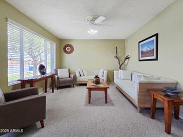 Bright living room with plush seating, ceiling fan, and large window bringing natural light to this spacious home at 3108 W Butler Dr, Phoenix, AZ 85051