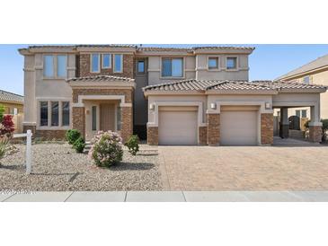 Two-story home with stone accents, a paver driveway, a two-car garage, and a desert-landscaped front yard at 5557 W Mine Trl, Phoenix, AZ 85083