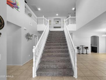 Bright entryway featuring a grand staircase with white railings and tiled floors at 13637 W Port Royale Ln, Surprise, AZ 85379