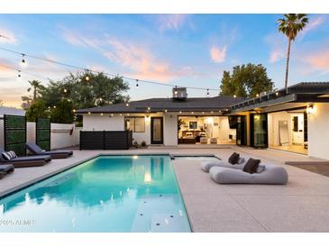 Lush backyard with a shimmering pool and jacuzzi, and views into the open layout of the home at 1609 W State Ave, Phoenix, AZ 85021