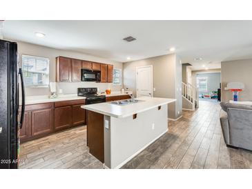 Well-lit kitchen featuring an island, modern appliances, wooden cabinets, and wood-look tile flooring at 16562 W Sierra St, Surprise, AZ 85388