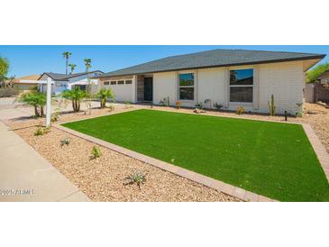 Charming single-story home with a well-maintained front yard featuring artificial grass and desert landscaping at 17411 N 36Th St, Phoenix, AZ 85032