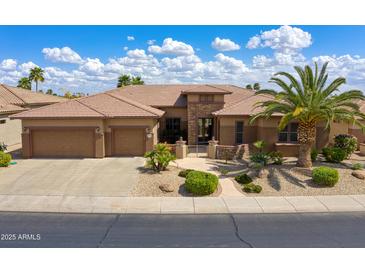 Beautiful single-story home showcasing manicured landscaping, a spacious three-car garage, and gated entry at 20609 N Canyon Whisper Dr, Surprise, AZ 85387