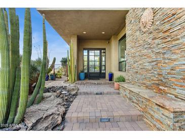 Inviting front entrance with stone accents, desert landscaping, and a modern glass door at 38199 N Tranquil Way, Carefree, AZ 85377