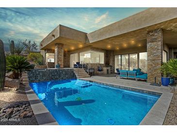Inviting backyard pool with a stone accent wall and modern outdoor furniture, perfect for relaxation at 38199 N Tranquil Way, Carefree, AZ 85377