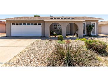 Charming single-story home featuring a well-maintained front yard, a two-car garage, and arched front entryway at 5221 W Garden Dr, Glendale, AZ 85304