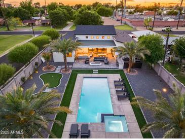 Expansive backyard boasts a sparkling pool, putting green, outdoor seating, and a firepit for memorable entertaining at 6301 N 16Th Dr, Phoenix, AZ 85015