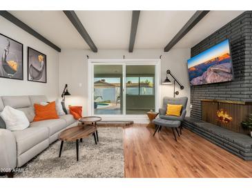 Living room with natural light, a fireplace, and seamless indoor-outdoor flow to the backyard pool at 8431 E Rose Ln, Scottsdale, AZ 85250