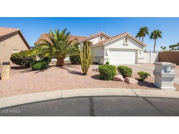 Charming single-story home featuring desert landscaping, mature trees, and a well-maintained two-car garage at 15516 W Verde Ln, Goodyear, AZ 85395