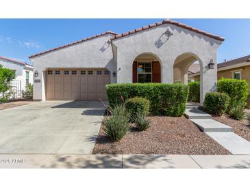 Charming single-story home with neutral stucco, arched entryway, red tile roof and two-car garage at 20698 W Meadowbrook Ave, Buckeye, AZ 85396