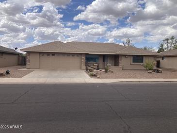 Tan home showcasing a desert landscaped front yard, stone accents, and a two-car garage, under a bright, partly cloudy sky at 2152 S Olivewood --, Mesa, AZ 85209