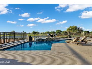 Backyard pool with tiled water feature, stone surround, lounge chairs, and views of a lake at 3842 E Alameda Ln, Gilbert, AZ 85298