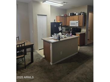 View of a kitchen featuring an island, wooden cabinets, and a refrigerator at 6629 W Polk St, Phoenix, AZ 85043