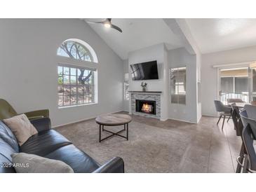 Bright living room with vaulted ceilings, modern fireplace, and a large window showcasing desert views at 7675 E Mcdonald Dr # 107, Scottsdale, AZ 85250