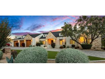 Charming single-story home featuring stone accents, manicured landscaping, and a three-car garage at 8220 E Sharon Dr, Scottsdale, AZ 85260