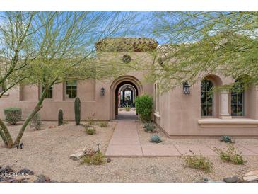 Inviting arched entryway with a desert landscape, creating a warm and welcoming feel to this home at 10799 E Florence Way, Scottsdale, AZ 85262