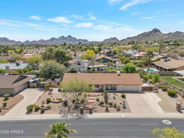 Charming single-story home featuring desert landscaping and a spacious driveway, set against a backdrop of scenic mountains at 2315 E Cholla St, Phoenix, AZ 85028