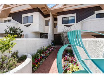 Inviting exterior featuring a quaint brick walkway with vibrant floral landscaping and unique architectural details at 33 W Missouri Ave # 17, Phoenix, AZ 85013