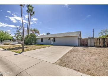 Single-story home with palm trees, a manicured lawn, and a driveway leading to the front entrance at 7135 E Baywood Ave, Mesa, AZ 85208